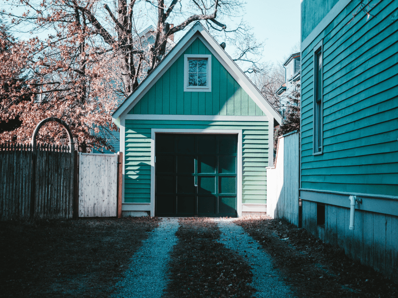 Green garage with a small window and a pine green garage door