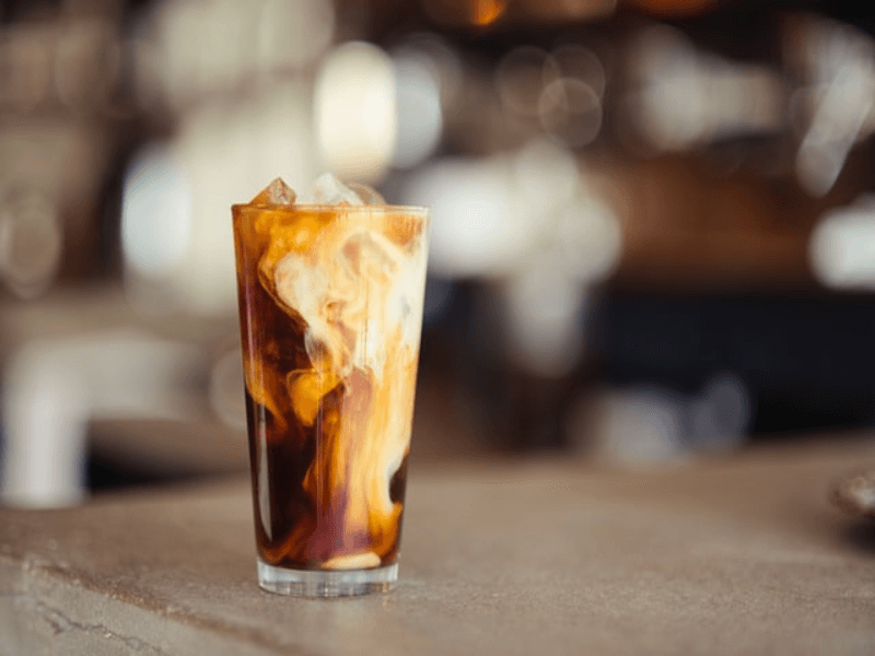 An iced coffee in a glass on top of a table.