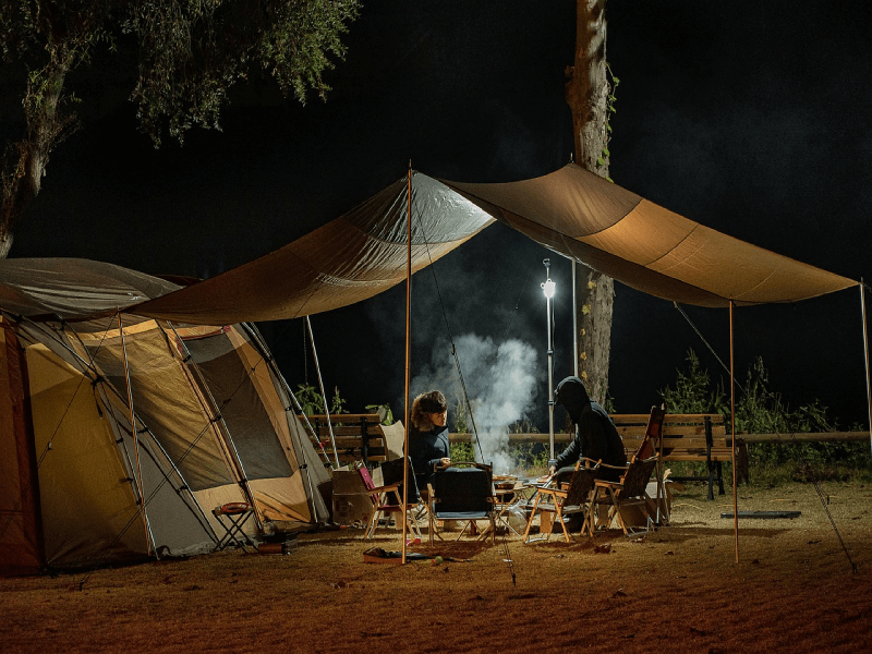 People sitting around a fire in warm clothes around their tent
